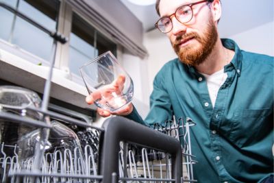 Personne tenant un verre rendu propre grâce à un lave-verre avec osmoseur.